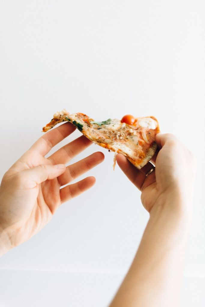 person holding a slice of pizza